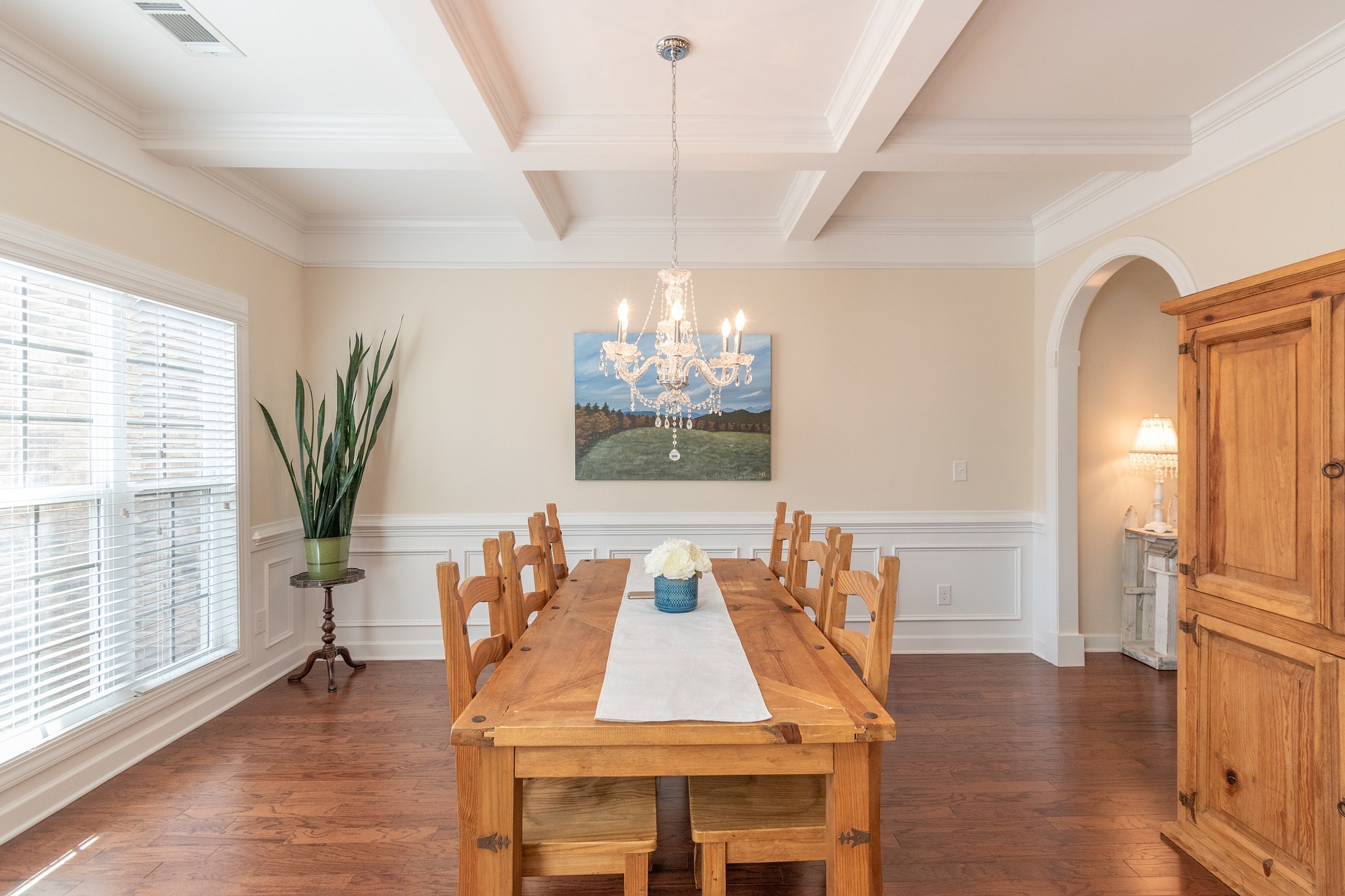 An image of a beautiful wooden dining table with wooden chairs and wonderful ceiling lamp